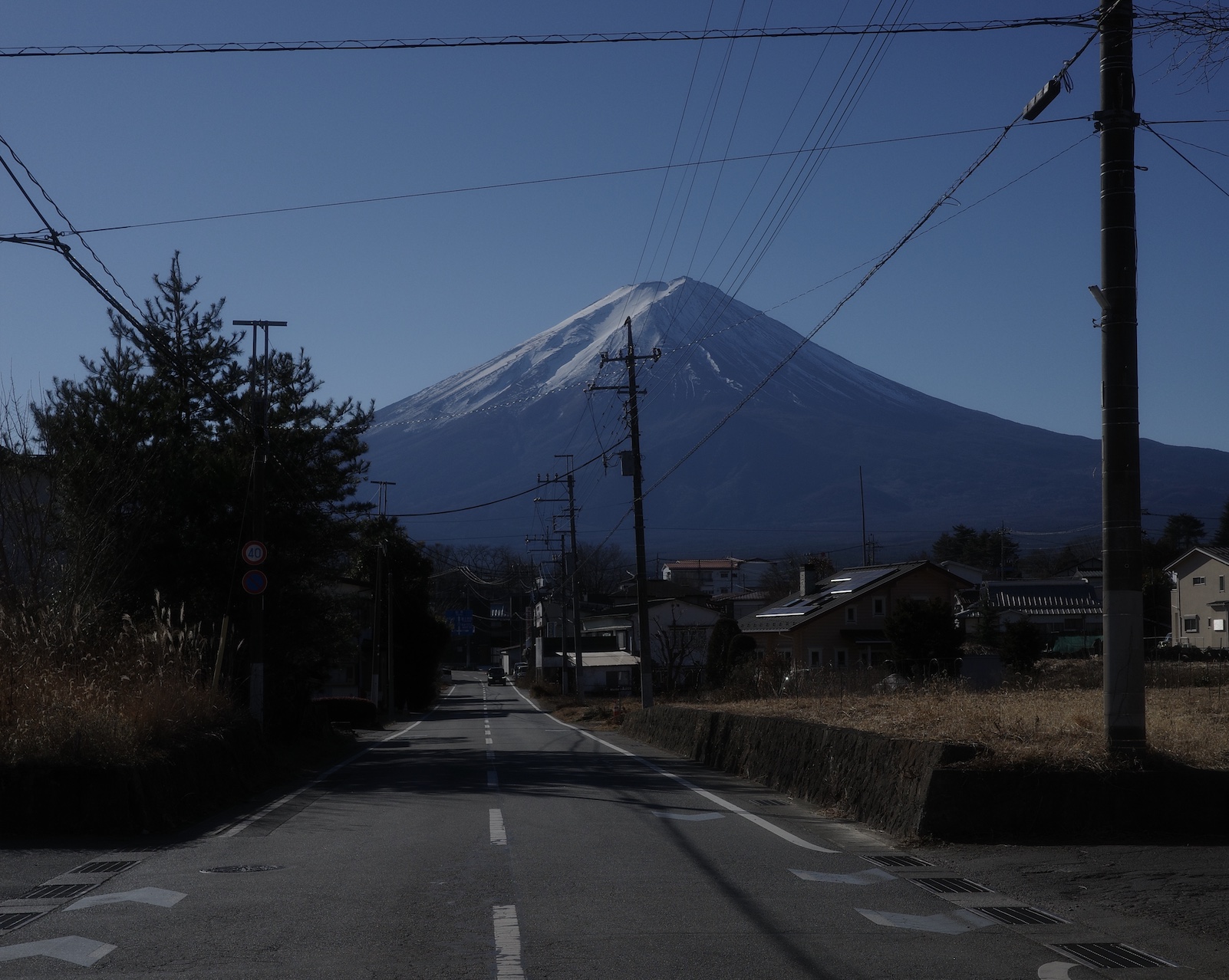Mount Fuji rising above a road and neighborhood in Japan